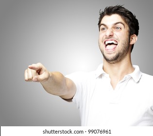 Portrait Of A Handsome Young Man Pointing And Joking Over Grey Background