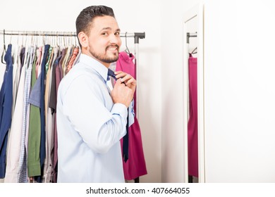 Portrait Of A Handsome Young Man Putting On A Necktie And Getting Dressed In A Dressing Room At Home