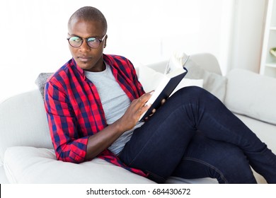 Portrait Of Handsome Young Man Reading A Book At Home.