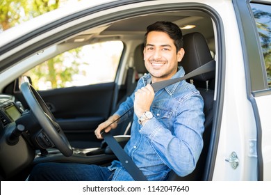 Portrait Of Handsome Young Man Sitting In Driving Seat Of Car And Wearing Seatbelt For Safety