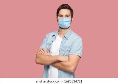 Portrait of handsome young man with surgical medical mask in blue casual style shirt standing, raised arms and looking at camera with smile. indoor studio shot, isolated on pink background. - Powered by Shutterstock