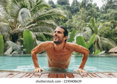 Portrait of handsome young man in swimming pool. Caucasian man in pool looking away and smiling. Male at luxury holiday resort. - Powered by Shutterstock