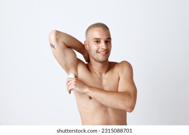 Portrait of handsome young man with well-kept skin, posing shirtless, using deodorant against white studio background. Concept of men's beauty, skincare, cosmetology, spa, health. Copy space for ad - Powered by Shutterstock