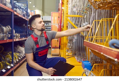 Portrait of a handsome young man who works as a salesman or manager at a modern DIY store, shopping mall or hardware retailing store crouching and checking goods in one of the aisles