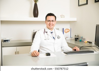 Portrait Of A Handsome Young Neurologist Sitting Behind A Desk In His Office And Smiling