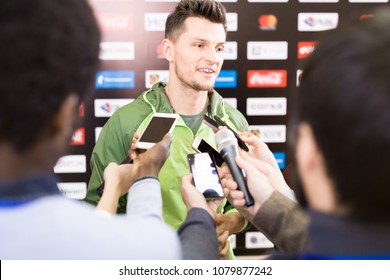 Portrait Of Handsome Young Sportsman Giving Interview To Group Of Journalists During Press Conference