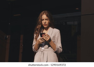 Portrait Of Handsome Young Woman With Long Hair And Pink Nails Holding Her Phone In Summer Outside