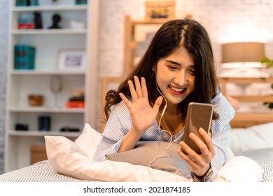 Portrait Of Happy 20s Aged Asian Woman In Casual Clothing Making Facetime Video Calling With Smartphone At Home. Using Conferencing Meeting Online App, Social Distancing, Work From Home Concept