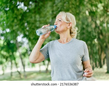 Portrait of a happy active beautiful senior woman holding a bottle of water posing after exercicing outdoors  - Powered by Shutterstock