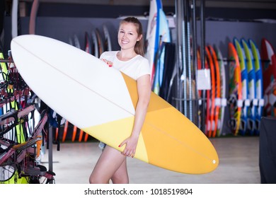 Portrait of happy active girl surfer holding new surfboard in nautical store - Shutterstock ID 1018519804