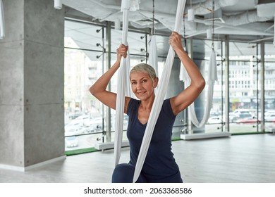 Portrait Of Happy Active Middle-aged Caucasian Woman On Hammock Practice Fly Yoga Stretching In Fitness Club. Smiling Sporty 50s Female Do Sports Exercise Training Workout Follow Healthy Lifestyle.