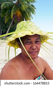 Portrait Of A Happy Active Senior  Polynesian Pacific Islander Tahitian Woman, Wearing Handcraft Hat Knees Out Of Palm Leaves In A Beach In Aitutaki Lagoon, Cook Islands.Real People. Copy Space