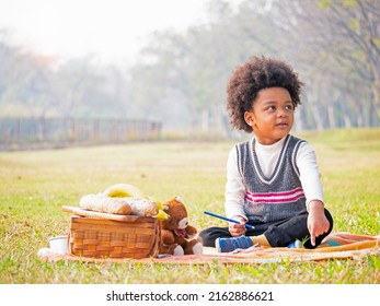 Portrait of the happy African American boy setting picnic table in the garden in the beautiful morning.