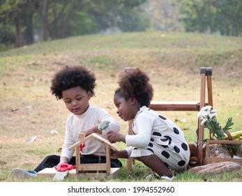 Portrait of the happy African American boys and girls setting picnic table in the garden in the beautiful morning. Adventure kindergarten day trip into wild nature.