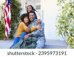 Portrait of happy african american family embracing outside home with usa flag, copy space. Expression, togetherness, military, army, protection, duty, patriotism and nationality, unaltered.