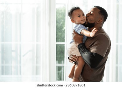 Portrait happy African American father with baby in arms standing near window at home	 - Powered by Shutterstock