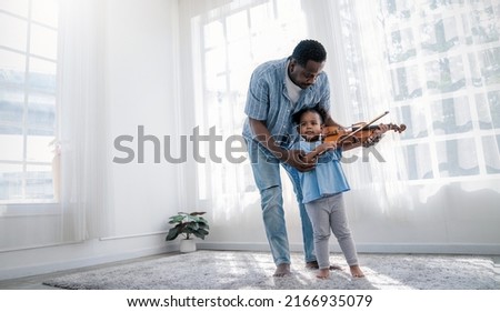 Portrait of happy African American father, teacher and little black girl daughter playing violins. Family leisure time doing hobby with music instrument. Love together fatherhood, Father's Day concept