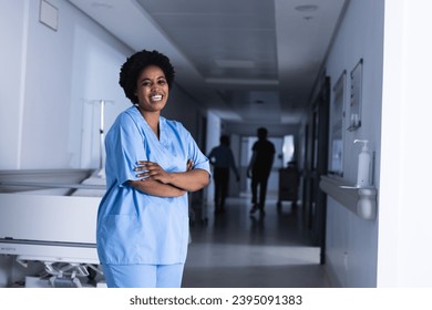 Portrait of happy african american female doctor in hospital corridor with copy space. Medicine, healthcare and medical services, unaltered. - Powered by Shutterstock