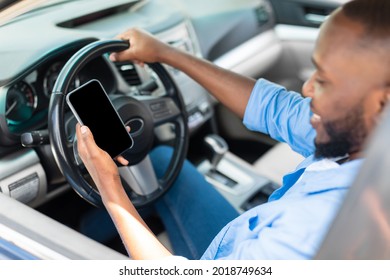 Portrait Of Happy African American Male Driver Holding And Using Smartphone With Black Blank Screen, Mock Up. Closeup Of Cellphone With Empty Display, Guy Using Mobile App For Navigation, Copy Space