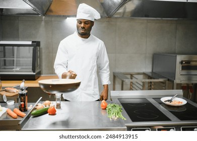 Portrait of happy African American male chef standing in restaurant kitchen. - Powered by Shutterstock