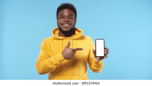 Portrait Of Happy African American Man Showing Blank Screen Mobile Phone Standing Isolated Over Blue Background.