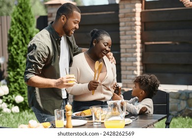 portrait of happy african american parents and son preparing table for lunch in garden on backyard - Powered by Shutterstock