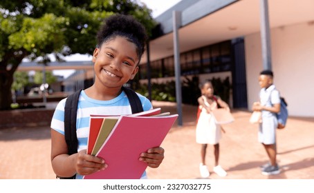 Portrait of happy african american schoolgirl standing in school yard. Education, childhood, elementary school and learning concept. - Powered by Shutterstock