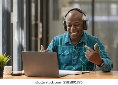 Portrait of happy African American senior man wearing headphones, enjoying working at home office. - Powered by Shutterstock