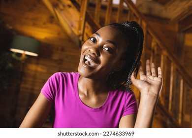 Portrait of happy african american woman spending time in log cabin and having video call. Log cabin, nature and lifestyle concept. - Powered by Shutterstock