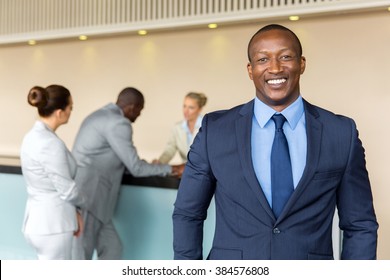 Portrait Of Happy African Businessman Standing At Hotel Reception