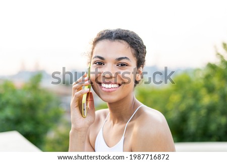 Portrait of a happy African girl with a stunning Smile talking on the mobile phone outside 