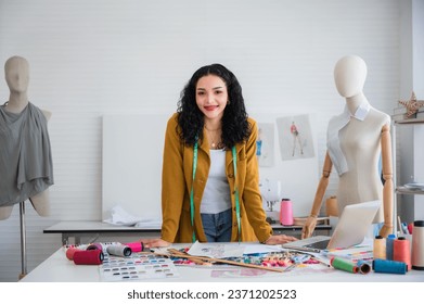 Portrait of happy African woman design dressmaker or seamstress tailor with a green tape measure and dummy mannequin standing smiling and looking at the camera in the fashion studio workplace. - Powered by Shutterstock