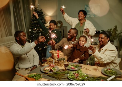 Portrait of happy African-American family lighting sparklers while enjoying Christmas at home together - Powered by Shutterstock