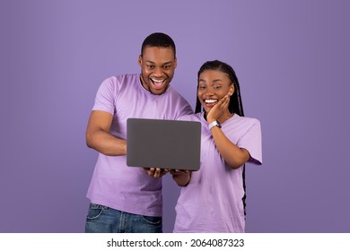 Portrait Of Happy Amazed African American Couple Holding And Using Laptop, Emotional Black Guy Showing Lady Something Exciting Content, Pointing At Notebook Screen Or Typing On Keyboard, Copy Space