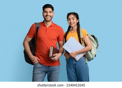 Portrait Of Happy Arab Student Couple With Backpacks And Books Posing Over Blue Studio Background, Young Middle Eastern Man And Woman Smiling At Camera, Enjoying Modern Education, Copy Space