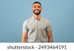 Portrait of happy arabic guy smiling at camera over blue studio background, copy space. Handsome middle-eastern young man in casual showing positive emotions