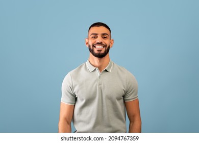 Portrait of happy arabic guy smiling at camera over blue studio background, copy space. Handsome middle-eastern young man in casual showing positive emotions