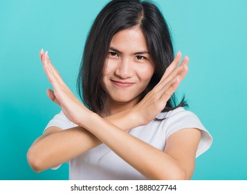 Portrait Happy Asian Beautiful Young Woman Unhappy Or Confident Standing Wear White T-shirt, She Holding Two Crossing Arms Say No X Sign, Studio Shot On Blue Background With Copy Space For Text