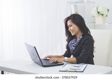 portrait of happy asian business woman using laptop computer while working