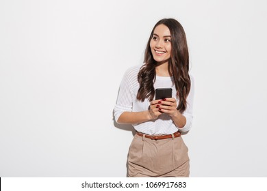 Portrait of a happy asian businesswoman holding mobile phone and looking away isolated over white background - Powered by Shutterstock