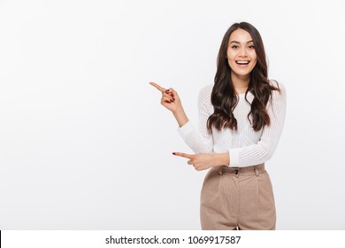 Portrait of a happy asian businesswoman pointing finger away at copy space isolated over white background - Powered by Shutterstock