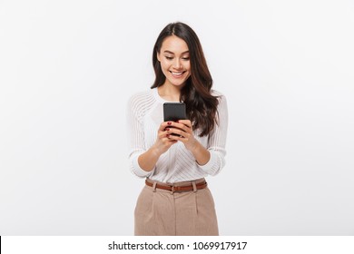 Portrait of a happy asian businesswoman using mobile phone isolated over white background