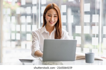 Portrait Of Happy Asian Businesswoman Using Laptop Computer While Working With Using A Calculator To Calculate The Numbers, Finance Accounting Concept