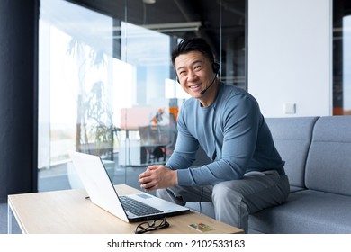 portrait of happy asian call center worker, man smiling and happy working with headset and computer, remote work, video call, online help
