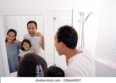 Portrait Of Happy Asian Family Brush Their Teeth Together In Bathroom Sink. Parent Brush Teeth And Take Care Of Kid