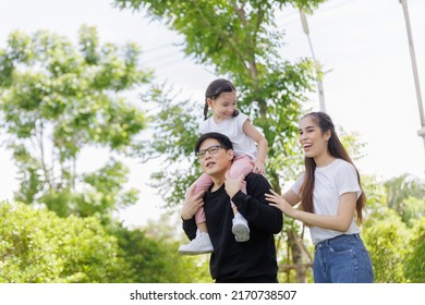 Portrait Of A Happy Asian Family Consisting Of Parents And Children Happy Together For The Holidays. Asian Family With A Child Playing On A Lawn, Enjoyment Relaxing Recreational Concept.