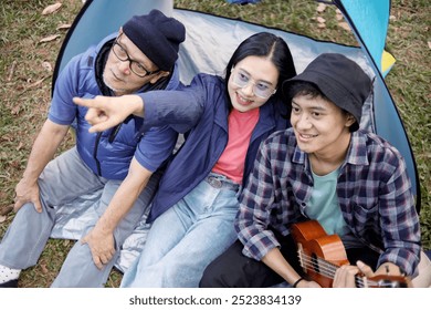 Portrait of happy Asian family enjoying picnic and camping at the campsite - Powered by Shutterstock