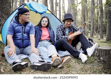 Portrait of happy Asian family enjoying picnic and camping at the campsite - Powered by Shutterstock