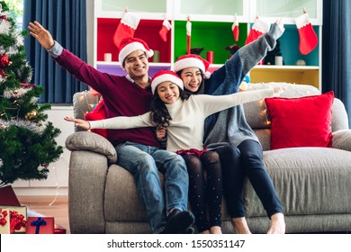 Portrait Of Happy Asian Family Father And Mother With Daughter In Santa Hats Having Fun Look At Camera And Enjoying Spending Time Together In Christmas Time At Home