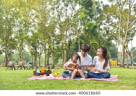 Portrait of happy Asian family, parents and daughter enjoying picnic meal in garden.Asian, Asian family, picnic, love, relationship, outdoors meal, park, family activities or happy garden concept